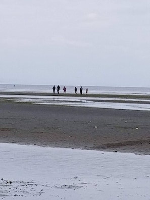 Una playa con gente caminando por la orilla.