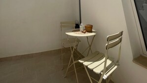 A small balcony with a table and two chairs, a string of lights, and a view of the sky. - Historic Holiday Home Il Melograno where tranquility reigns supreme (cavallino)