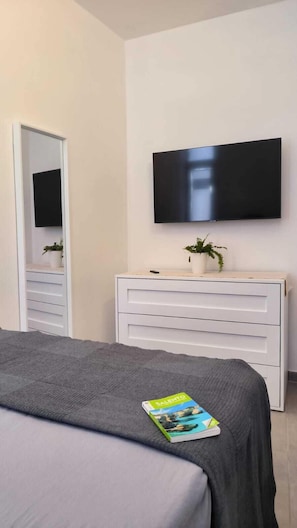 Une chambre à coucher avec un lit, une commode, un téléviseur et un miroir.
