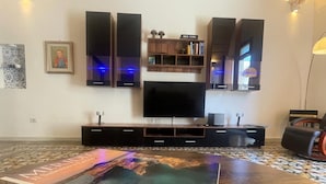 A living room with a large flat-screen TV, dark wooden entertainment unit, and a patterned rug. - Historic Holiday Home Il Melograno where tranquility reigns supreme (cavallino)