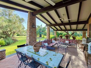 An outdoor patio with a stone column, a tiled table, and a sofa set.