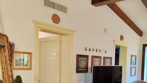 Una sala de estar con televisor, una cesta de mimbre y cuadros en la pared.