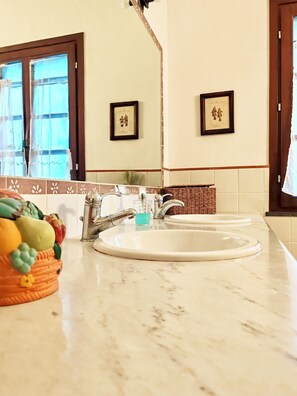 A bathroom with two sinks, a mirror, and a fruit bowl on the counter.