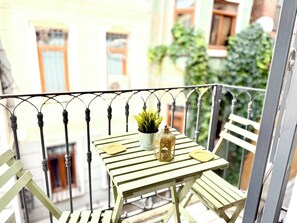 Ein Balkon mit einem kleinen Tisch, einem Blumentopf und einer Laterne.