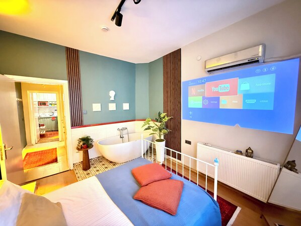 Ein modernes Schlafzimmer mit einem großen Bett, einer Badewanne und einem an der Wand montierten Fernseher, der eine Benutzeroberfläche zeigt.