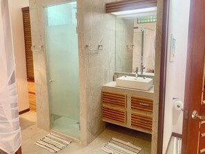 A bathroom with a glass-enclosed shower, a white sink, and wooden cabinetry.