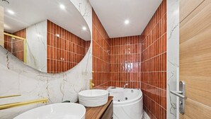 A modern bathroom with a curved mirror, two sinks, a bathtub, and red-tiled walls.