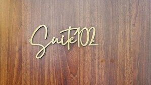 A wooden surface with the text "Suite 102" in a cursive font.