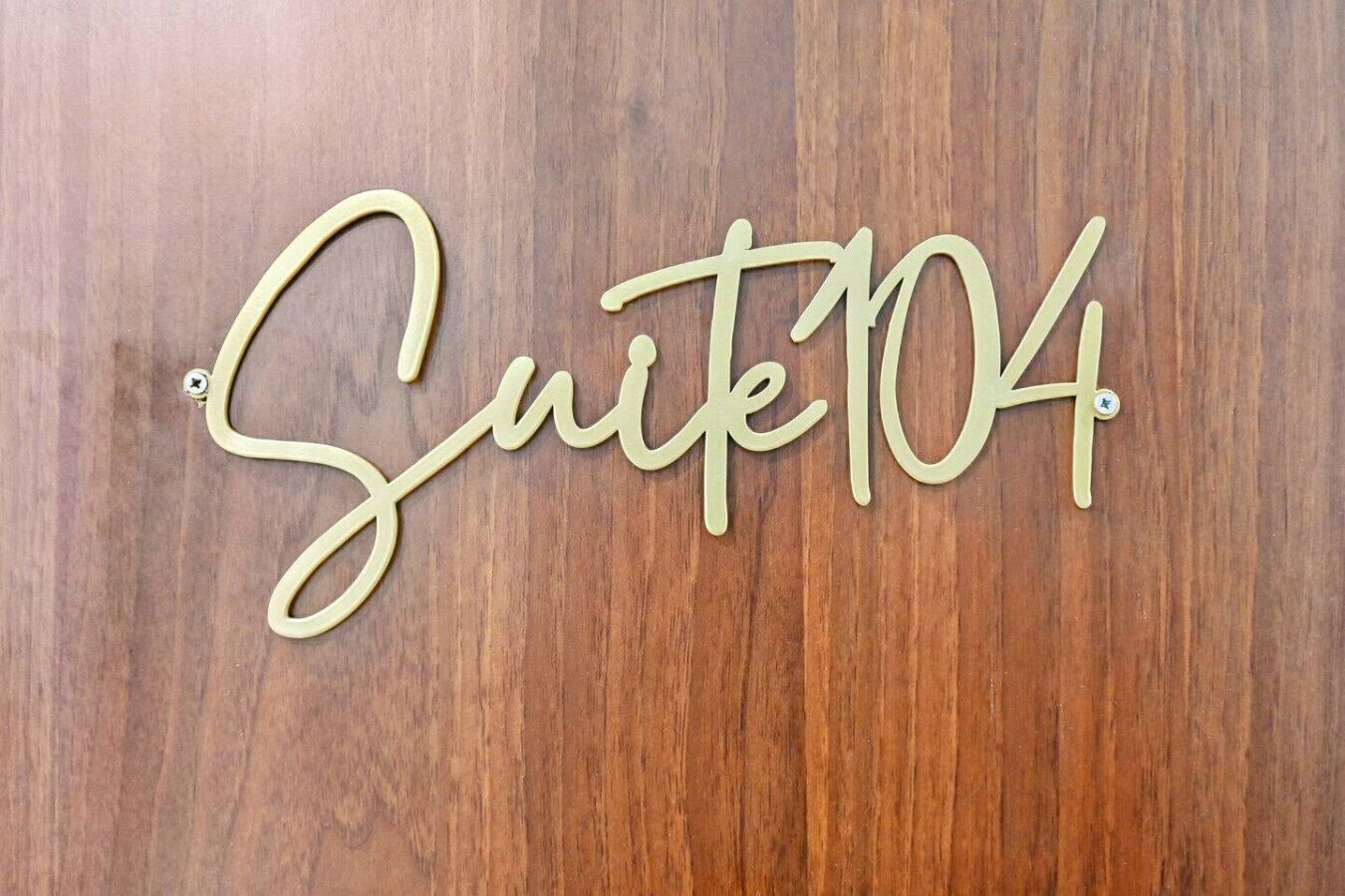 A wooden wall with the text "Suite 104" in a cursive font.