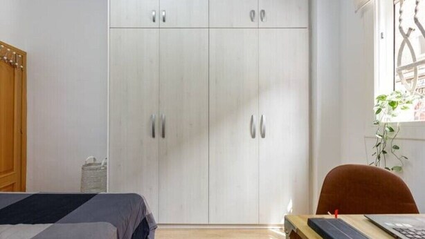 Un dormitorio con una cama, un escritorio con silla y un armario.