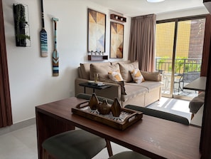 Un salon moderne comprenant un canapé, une table à manger et un balcon aménagé avec du mobilier d’extérieur.