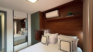 A hotel room with a bed, a mirror, an air conditioning unit, and a wooden headboard. - Jardins Almare 305 (Joao Pessoa)
