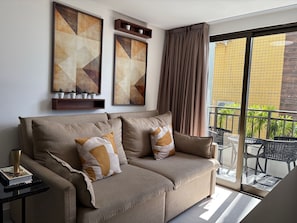 Een moderne woonkamer met een bank, decoratieve kussens, een salontafel en kunst aan de muur.