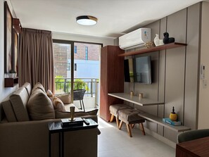 Ein modernes Wohnzimmer mit einer Couch, einem Couchtisch, einem Fernseher und einer Klimaanlage.