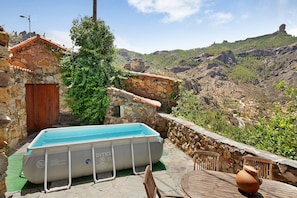 A stone building with a pool, a wooden door, and a view of a mountainous landscape. - Authentic Canarian House in the Center of Gran Canaria (Tejeda)