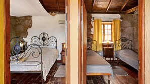 Une chambre avec deux lits, un mur en pierre et un plafond en bois.