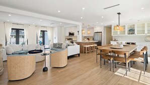 A modern living room with a sofa, a coffee table, and a dining area with a table and chairs.