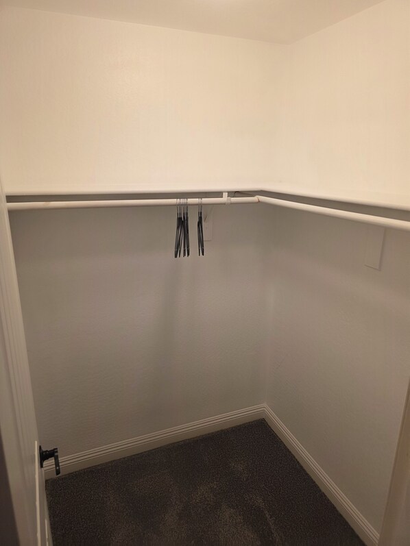 A small, empty room with white walls, a dark carpet, and a white ceiling.
