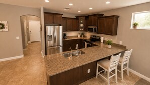Una cocina moderna con una isla central, electrodomésticos de acero inoxidable y armarios de madera oscura.
