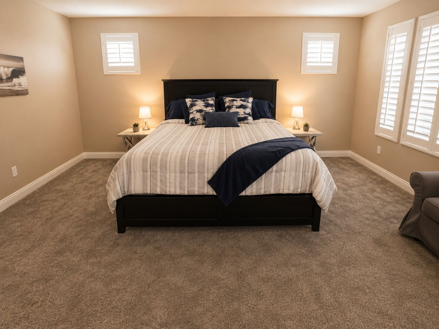 A bedroom with a bed, two bedside tables, a chair, and a window with blinds.