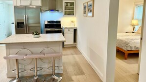 Una cocina moderna con una isla central, electrodomésticos de acero inoxidable y una zona de asientos con taburetes de bar.