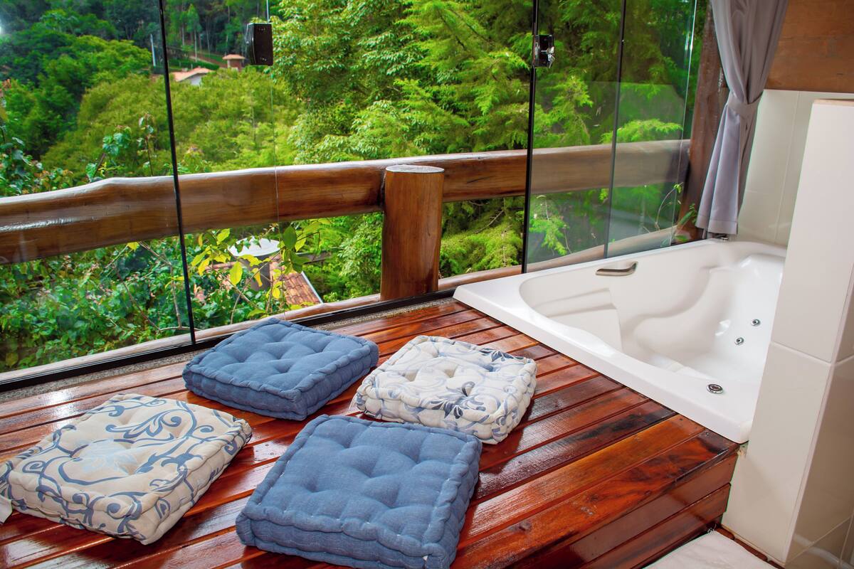 Une terrasse en bois avec une baignoire et trois coussins.