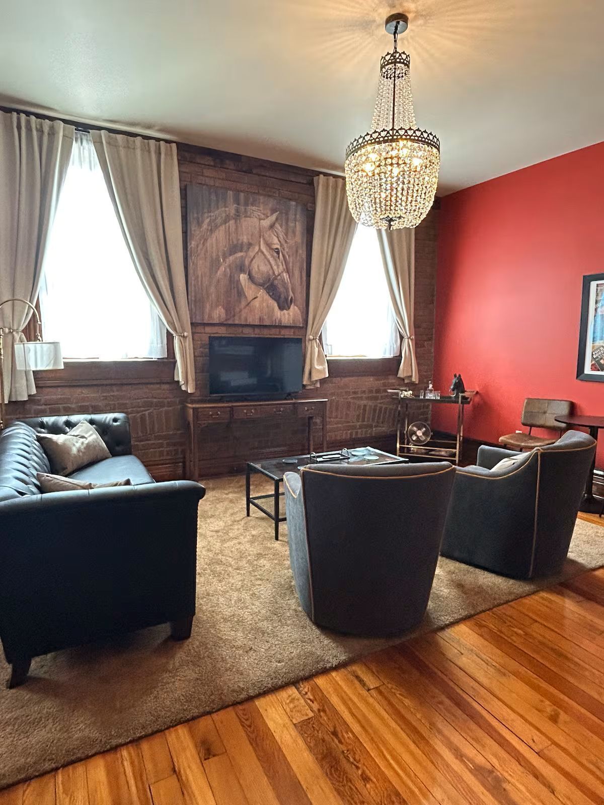 Un salon avec une cheminée, un canapé, deux fauteuils, une table basse et un lustre.