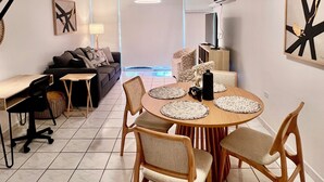 Ein modernes Wohnzimmer mit Essbereich, mit einem runden Tisch und Stühlen, einer Couch, einem Couchtisch und einer Treppe.