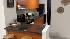 Eine moderne Küche mit Holzausstattung, einer Arbeitsplatte aus Granit und einer integrierten Kochinsel mit Barhocker.