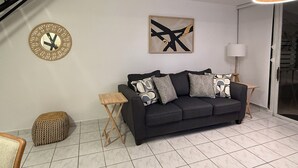Ein modernes Wohnzimmer mit einem schwarzen Sofa, einem Holztischchen, einer runden Wanduhr und einem modernen abstrakten Gemälde.