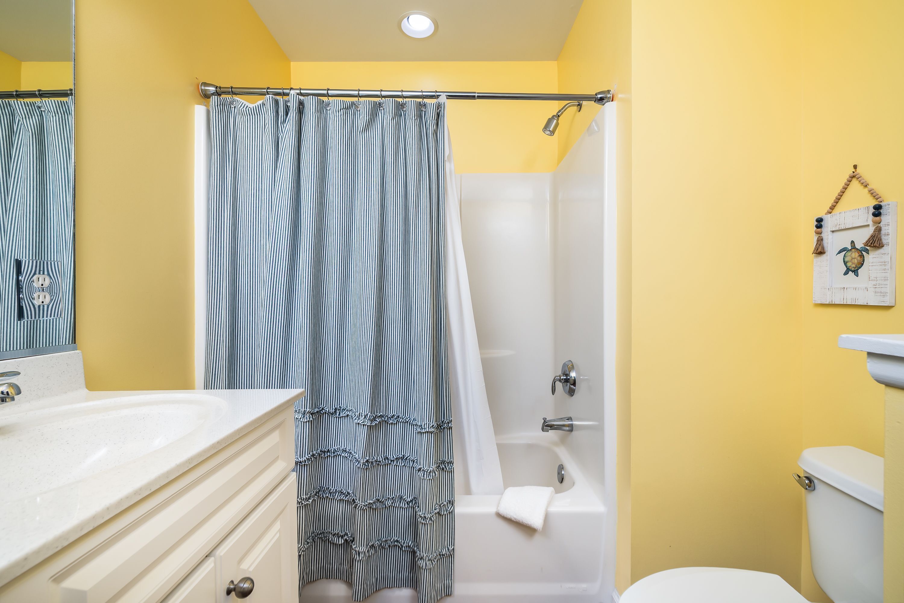 A bathroom with a white bathtub, a shower curtain, and a toilet.