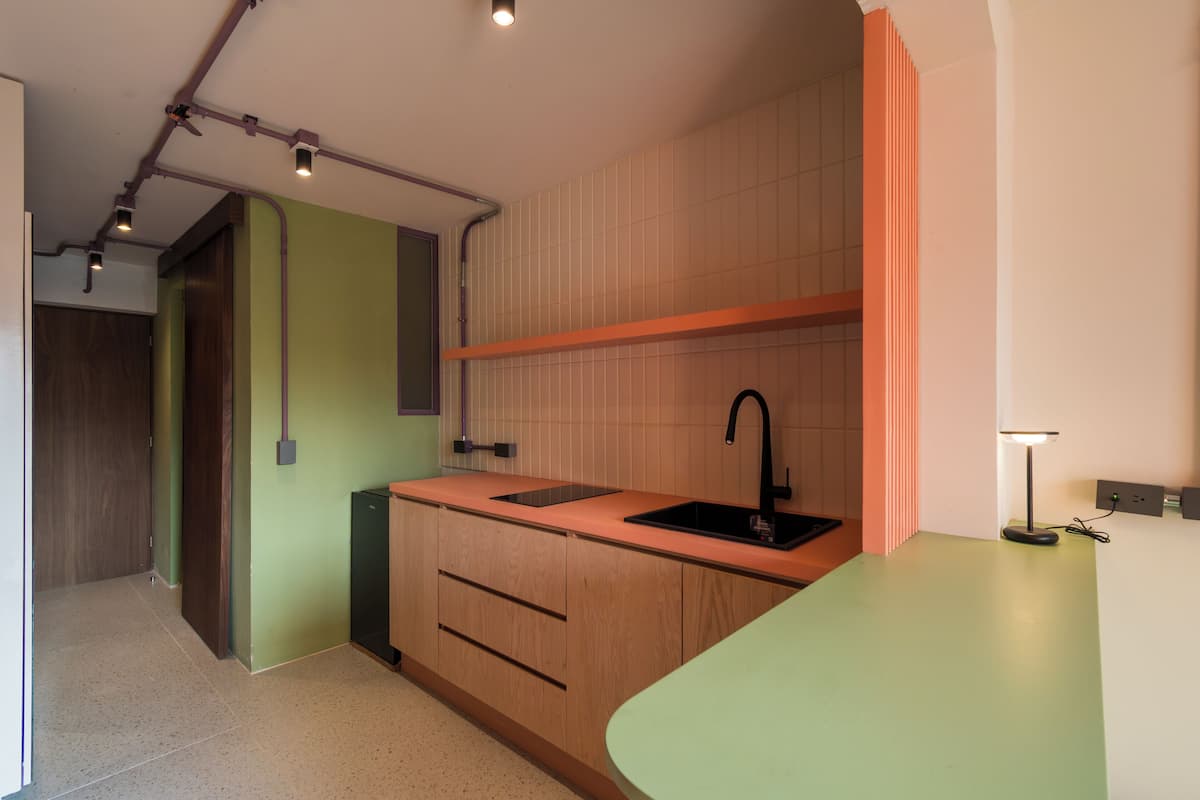 A modern kitchen with wooden cabinets, a black sink, and a green countertop.