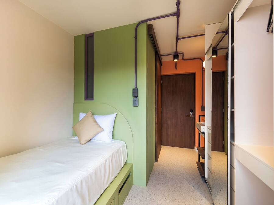 Un dormitorio con una cama, una pared verde y una puerta de madera.