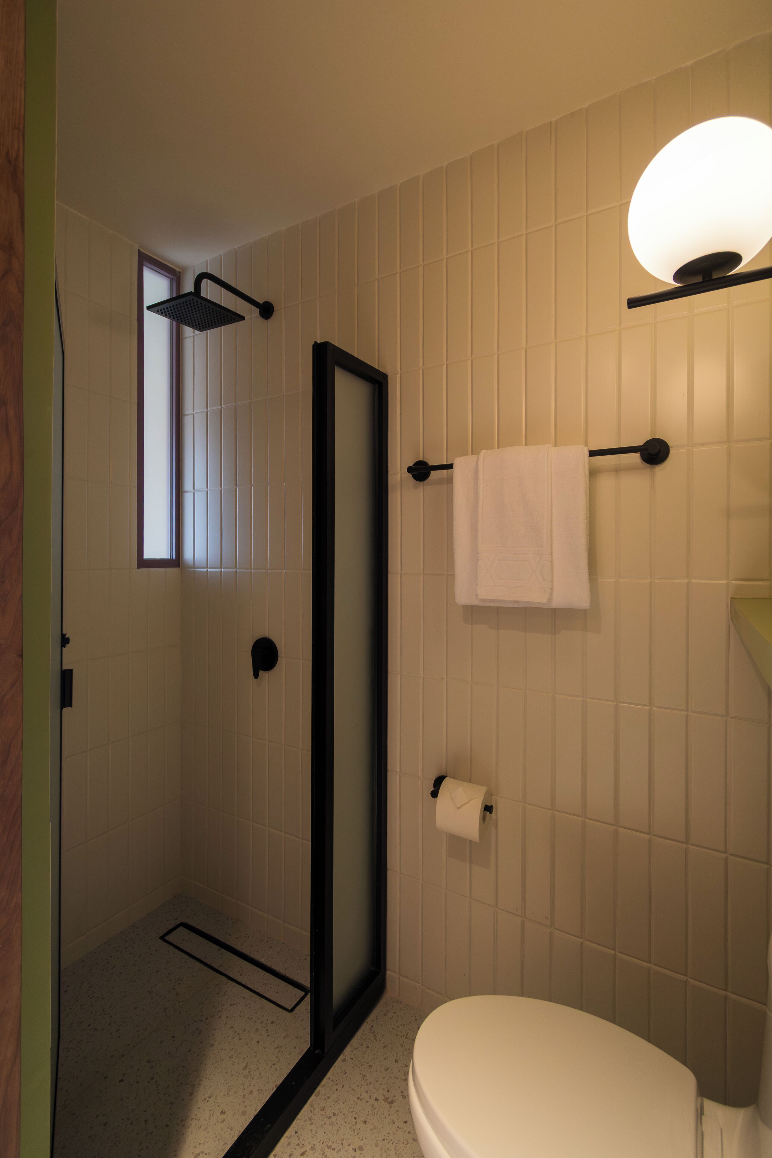 A bathroom with a shower, toilet, and a towel rack.