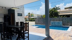 A covered outdoor area with a pool, dining table, and chairs.