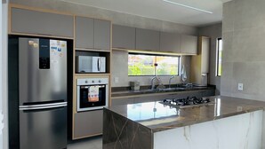A modern kitchen with a central island, built-in appliances, and a large window providing natural light.