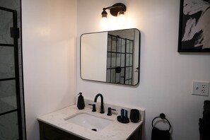 A bathroom with a white marble sink, black faucet, and a mirror with a black frame. - Hidden Sanctuary (Hagerstown, MD) (Hagerstown)