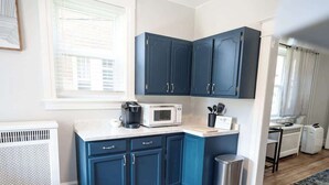A modern kitchen with dark blue cabinets, a white countertop, a microwave, and a coffee maker. - Hamilton Hideaway (Hagerstown, MD) (Hagerstown)
