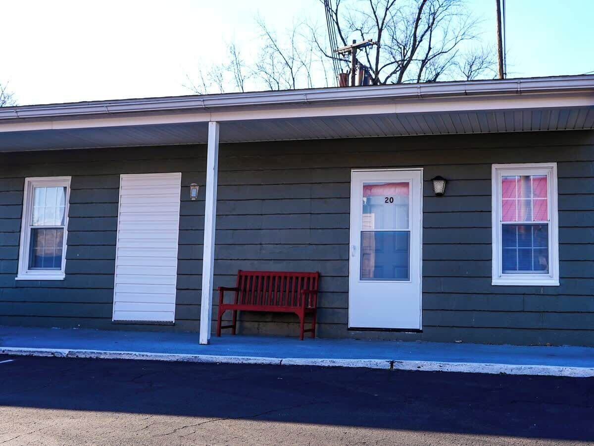 A single-story building with a porch, a bench, and two doors.