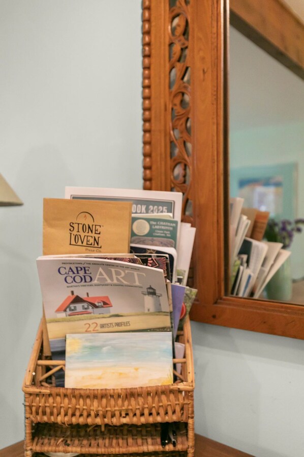 A wicker basket filled with magazines and a book titled "Cape Cod Art."