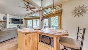 Una cocina con isla de madera, microondas integrado y ventilador de techo.