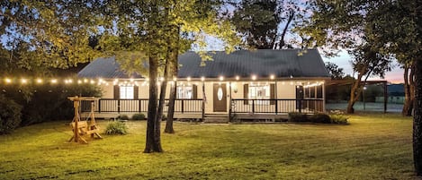 A house with a porch, a swing set, and string lights.