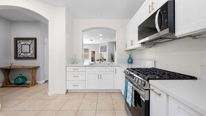 Een moderne keuken met witte kastjes, een gasfornuis en een magnetron.