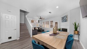 Een moderne eethoek met een houten tafel, blauwe fauteuils en een decoratieve vaas.