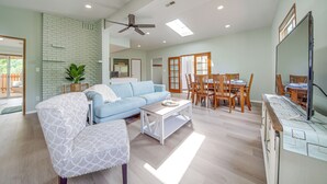 A spacious living room with a blue sofa, a white armchair, a wooden coffee table, and a dining area with wooden chairs and a table. - < 1 Mi to Lake Washington: Peaceful Apt in Kenmore (Kenmore)