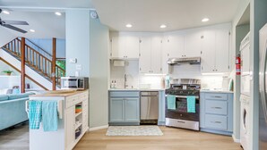 A modern kitchen with white cabinets, a microwave, a dishwasher, and a stove. There is a wooden staircase leading to another room. - < 1 Mi to Lake Washington: Peaceful Apt in Kenmore (Kenmore)