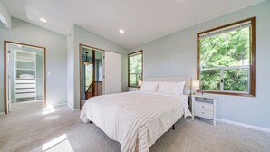 A bedroom with a large bed, a nightstand, a window with a view of trees, and a closet with a mirror. - < 1 Mi to Lake Washington: Peaceful Apt in Kenmore (Kenmore)