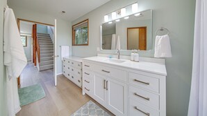 A modern bathroom with a large mirror, white vanity, and a shower area visible through an open door. - < 1 Mi to Lake Washington: Peaceful Apt in Kenmore (Kenmore)
