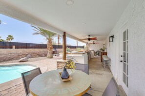 Un patio techado con piscina, mobiliario exterior y un ventilador de techo.