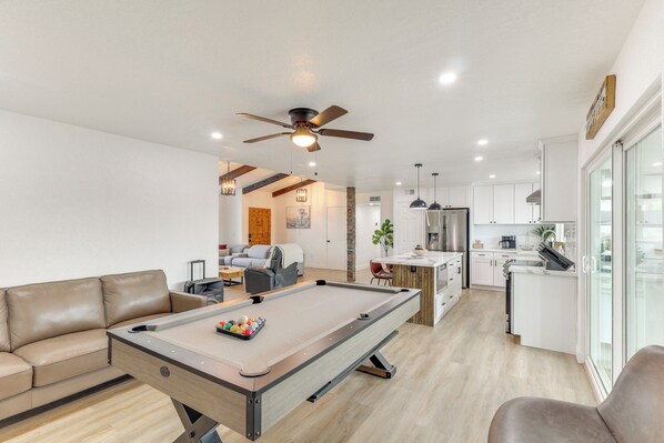 A modern living room with a pool table, a sofa, and a ceiling fan. - Poolside Relaxation: Group-Friendly Home in Havasu (Lake Havasu City)